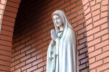 Ftima Anıtı, Katolik dininde Tanrı 'nın annesi, Fatima' nın Hanımı, Brezilya 'da tuğla bir duvarın arka planında Bakire Meryem' in heykeli.