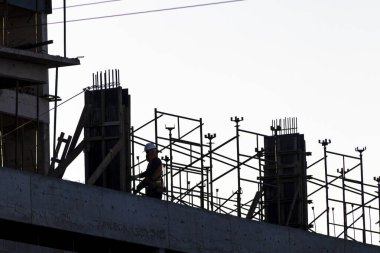 İnşaat alanı, gün batımına karşı iskelede çalışan inşaat işçilerinin siluetleri. Brezilya 'da inşaat ve inşaat endüstrisi