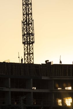 İnşaat alanı, gün batımına karşı iskelede çalışan inşaat işçilerinin siluetleri. Brezilya 'da inşaat ve inşaat endüstrisi