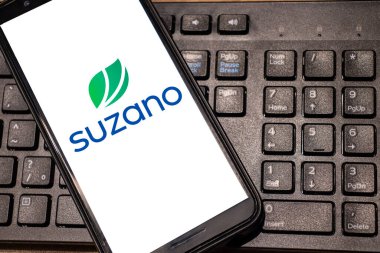 Sao Paulo, Brazil, May 05, 2024. Suzano logo is seen on an smartphone with PC keyboard background in Brazil clipart