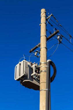 Brezilya 'da mavi gökyüzü arkaplanı olan bir direkte elektrik transformatörü.