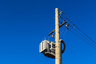 Brezilya 'da mavi gökyüzü arkaplanı olan bir direkte elektrik transformatörü.