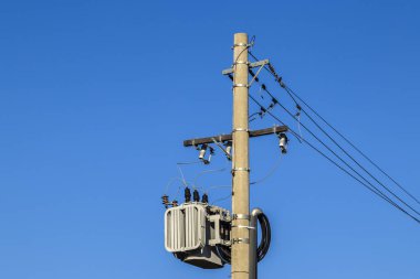 Brezilya 'da mavi gökyüzü arkaplanı olan bir direkte elektrik transformatörü.