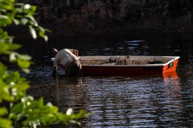 Marilia, Sao Paulo, Brezilya, 28 Haziran 2023. Bir kamu temizlik çalışanı, Marilia şehrindeki bir gölden çöp toplayan bir tekneyle çalışıyor.