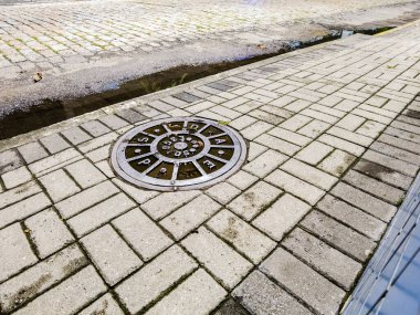 Iron manhole cover for access to the sewage system on a sidewalk in the city of Sao Paulo, Brazil clipart