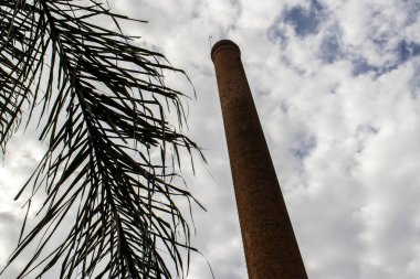 Tuğlalardan, kuru palmiye yapraklarından ve Brezilya 'da arka planda birçok bulutla inşa edilmiş bir baca.
