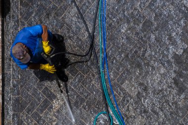 Sao Paulo, Brezilya, 23 Ocak 2025. Yüksek basınçlı su temizleyici ile çalışan işçi Brezilya 'da bir taş yüzeyi temizliyor.