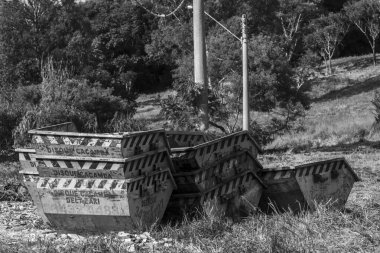 Sao Paulo, Brezilya, 23 Şubat 2025. Boş bir arazide istiflenmiş çöp konteynırlarının siyah beyaz görüntüsü. Kentsel atık yönetimi, çevresel etki ve geri dönüşüm önemini anımsatıyor