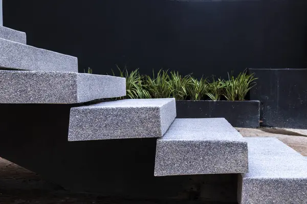 Açık havada modern granit merdivenlerin yakın çekimi, yeşil bitki örtüsüyle yan yana. Bu resim, taşın dayanıklılığını ve dokusunu vurgulayarak çağdaş mimari tasarımı iletir.