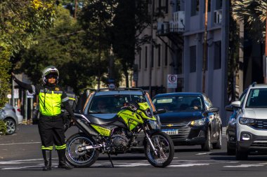 Marilia, SP, Brezilya, Mayıs 01, 2025. Marilia caddesinde trafik polisi trafiği yönetiyor. Memur, motosiklet ve arabalar görünüyor. Görüntü: Kentsel hareketlilik ve güvenlikle ilgili