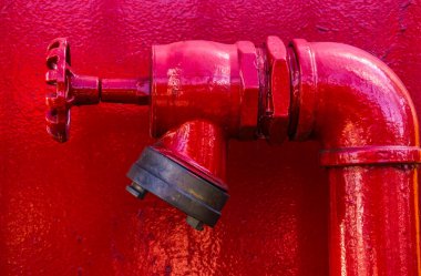 Canlı kırmızı bir yangın musluğu bağlantısına yakın çekim. Yangın koruma sistemleri için önemli bir unsur ve güvenlik ve önleme için bir örnektir.