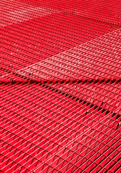 Kırmızı metal şebeke, çapraz desen. Karışık çubuklar geometrik bir doku oluşturur. Mimari, endüstri veya soyut tasarım kavramları için uygundur.