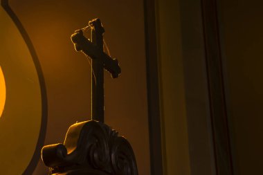 Brezilya 'da bir Katolik kilisesinde loş ışıkta yıkanan ahşap haç ve karmaşık detaylar. İnancı, tarihi ve kültürü çağrıştırıyor. Dini, tarihi veya sanat temaları için ideal.