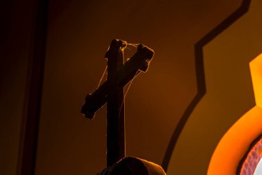 Brezilya 'da bir Katolik kilisesinde loş ışıkta yıkanan ahşap haç ve karmaşık detaylar. İnancı, tarihi ve kültürü çağrıştırıyor. Dini, tarihi veya sanat temaları için ideal.