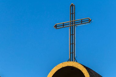 Metal haç açık mavi gökyüzüne karşı. Basit ama çarpıcı bir görüntü, inanç, din ve mimari kavramlar için idealdir..