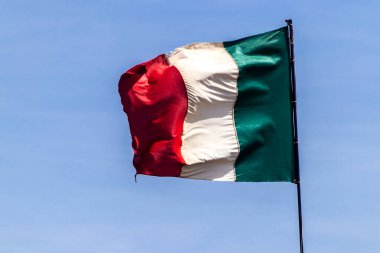 Açık mavi gökyüzünde sallanan İtalyan bayrağı. İtalya 'nın ulusal sembolü.