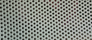 Eşit aralıklı yuvarlak deliklerle metalik delikli bir yüzeye yakın çekim. Tasarım, dekorasyon, havalandırma veya akustik paneller için uygun soyut endüstriyel doku. Yaratıcı projeler ve teknik illüstrasyon için tarafsız modern arkaplan