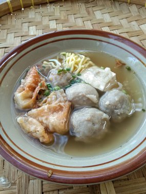 Örülmüş bambu arka planında çeşitli aksesuarlarla bir kase köfte.