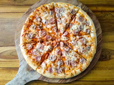 Basit malzemeli ev yapımı pizza, mozzarella ve ahşap tepside sosis.