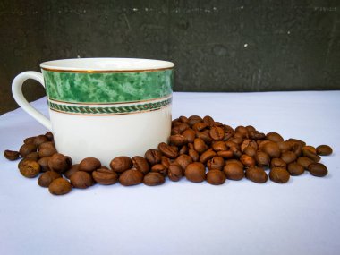 Kahve fincanı ve beyaz arka planda orta pişmiş kahve çekirdekleri.