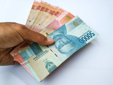 Endonezyalı bir adamın elinde 100,000 ve 50,000 banknot