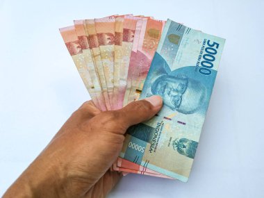 Endonezyalı bir adamın elinde 100,000 ve 50,000 banknot