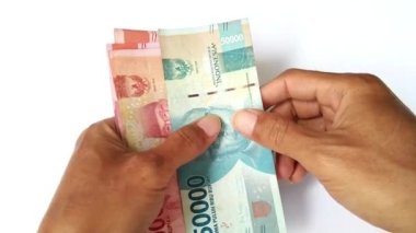 Asyalı adamın elleri beyaz bir arka planda Endonezya rupia paralarını sayıyor