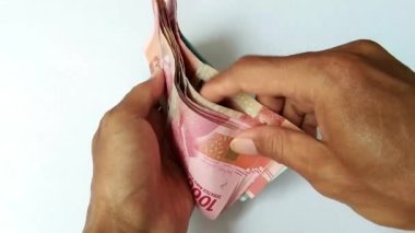 Asyalı adamın elleri beyaz bir arka planda Endonezya rupia paralarını sayıyor