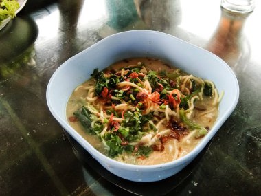 noodle soup in a white bowl on a wooden table