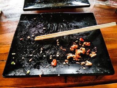 dirty black plates and chopsticks from leftover food