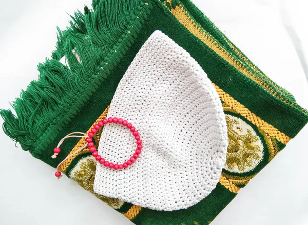 Muslim prayer kits consisting of prayer rugs, caps and tasbih with a white background