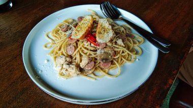 Beyaz seramik tabakta ahşap masa arkaplanlı spagetti.