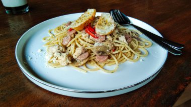 Beyaz seramik tabakta ahşap masa arkaplanlı spagetti.