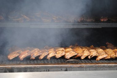 Ribs smoking on a grill in Detroit. Smoke can be seen coming from the heat of the grill as the ribs cook.