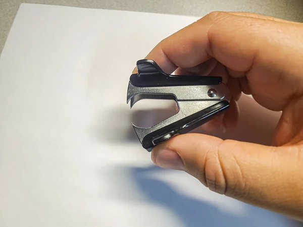 stock image A hand holding a stapler remover over a white sheet of paper