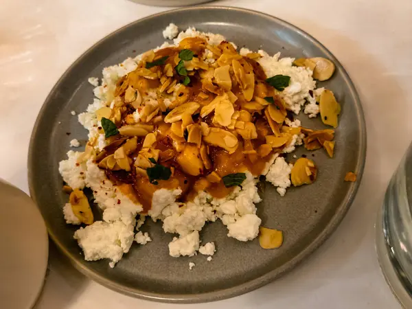 Bulgerian fetası, kayısı sosu, badem, aleppo, yağ, limon, otlar ve gri bir tabakta pide..