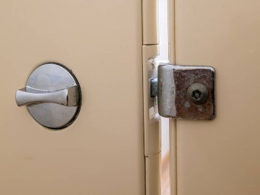 Açık sarı bir banyoda metal bir kilit.