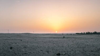 Güç hatlarının rehberliğinde çölde gün batımı.
