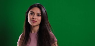 Stüdyoda genç ve güzel bir kadın yeşil arka planda poz veriyor. Stüdyo fotoğrafçılığı.