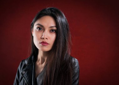 Kızıl arka plan karşısında kendine güvenen genç bir kadın. Stüdyo fotoğrafçılığı.