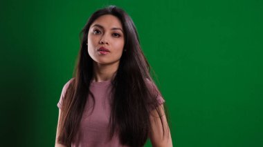 Stüdyoda genç ve güzel bir kadın yeşil arka planda poz veriyor. Stüdyo fotoğrafçılığı.
