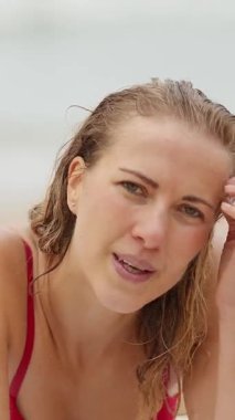 Güzel bir kadın, okyanusta bir sahilde kameraya poz veriyor. Seyahat fotoğrafçılığı.