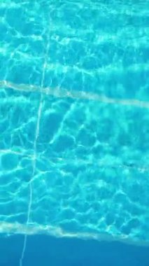 Genç bir kadın yaz mevsiminde serin bir havuzda yüzmeyi sever - yukarıdan bakıldığında - dikey video