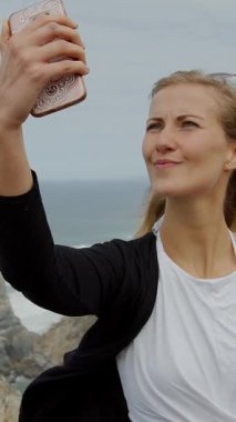 Genç bir kadın Portekiz 'deki Cape Roca' daki Ursa Plajı 'nda selfie çekiyor. Seyahat fotoğrafçılığı.