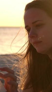 Genç bir kadın gün batımında sahilde yatarken kitap okur. Seyahat fotoğrafçılığı.