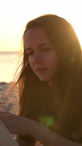 Junge Frau Liest Ein Buch Während Sie Bei Sonnenuntergang Strand — Stockvideo