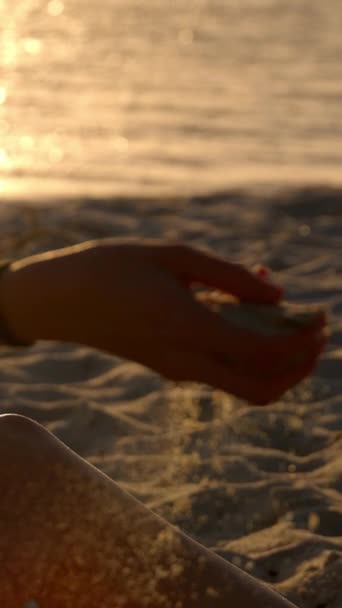 若い女性が夕日のビーチで砂と遊ぶ スローモーション 旅行写真 — ストック動画