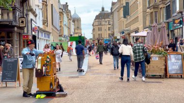 Street musician at Cornmarket Street Pedestrian zone in Oxford - OXFORD, UNITED KINGDOM - JUNE 10, 2022 clipart