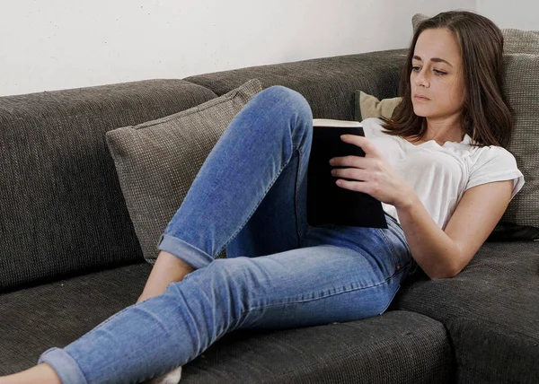 Young woman relaxes in the living room while reading a book - home shooting