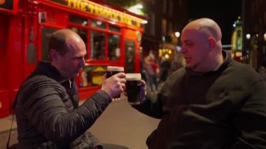 Two friends drinking a beer in the Temple Bar district of Dublin by night - Ireland travel photography